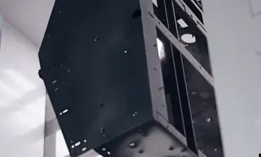 A large, multi-sided black metal enclosure or chassis assembly suspended vertically. The fabricated sheet metal structure features various pre-drilled holes, cutouts, and internal reinforcement brackets.