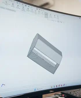 A computer monitor displaying a 3D CAD model of a sheet metal component in SolidWorks software